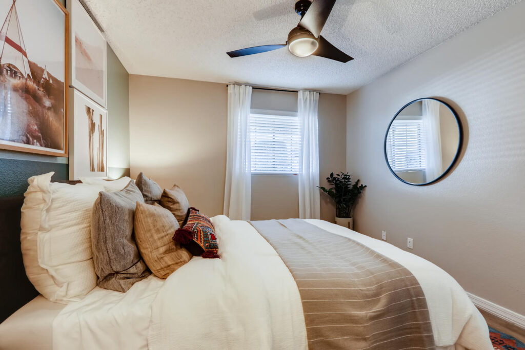 staged bedroom with ceiling fan and green accent wall