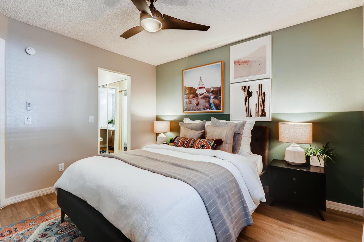 staged bedroom with ceiling fan and private bathroom, green accent wall