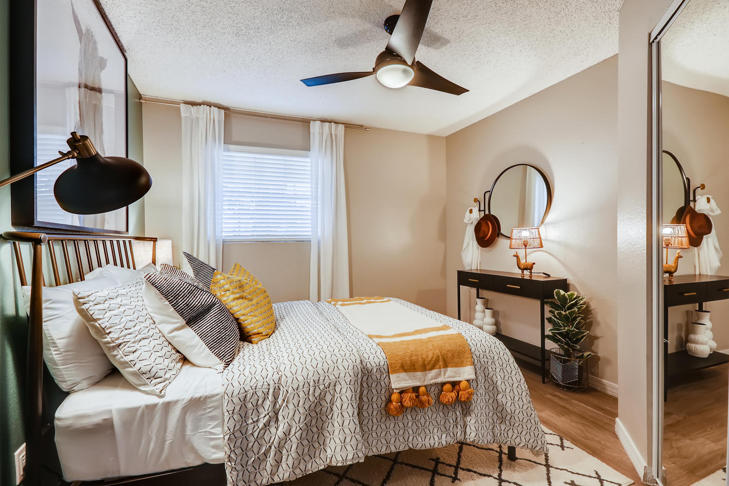staged bedroom with ceiling fan and mirrored closet