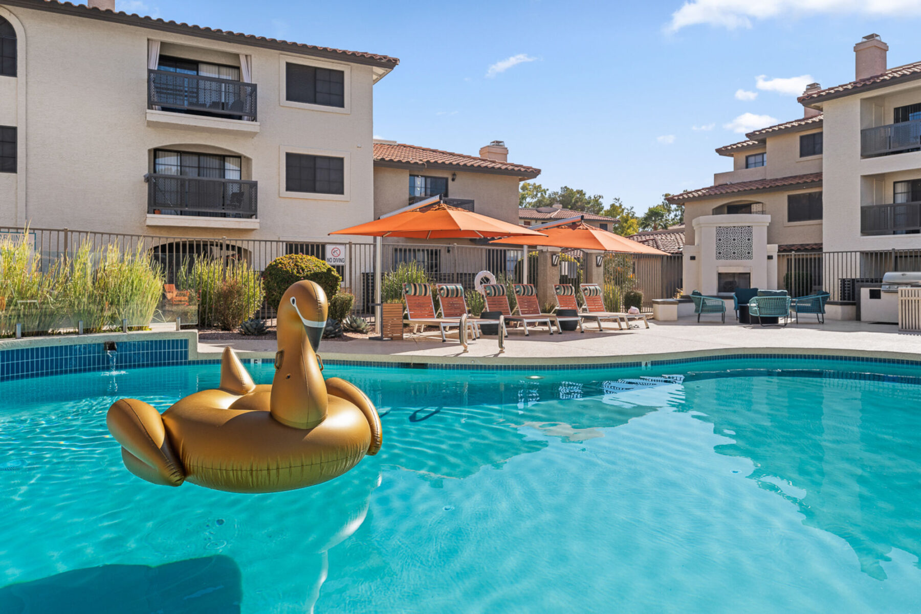 Pool with deck seating and tables with umbrellas